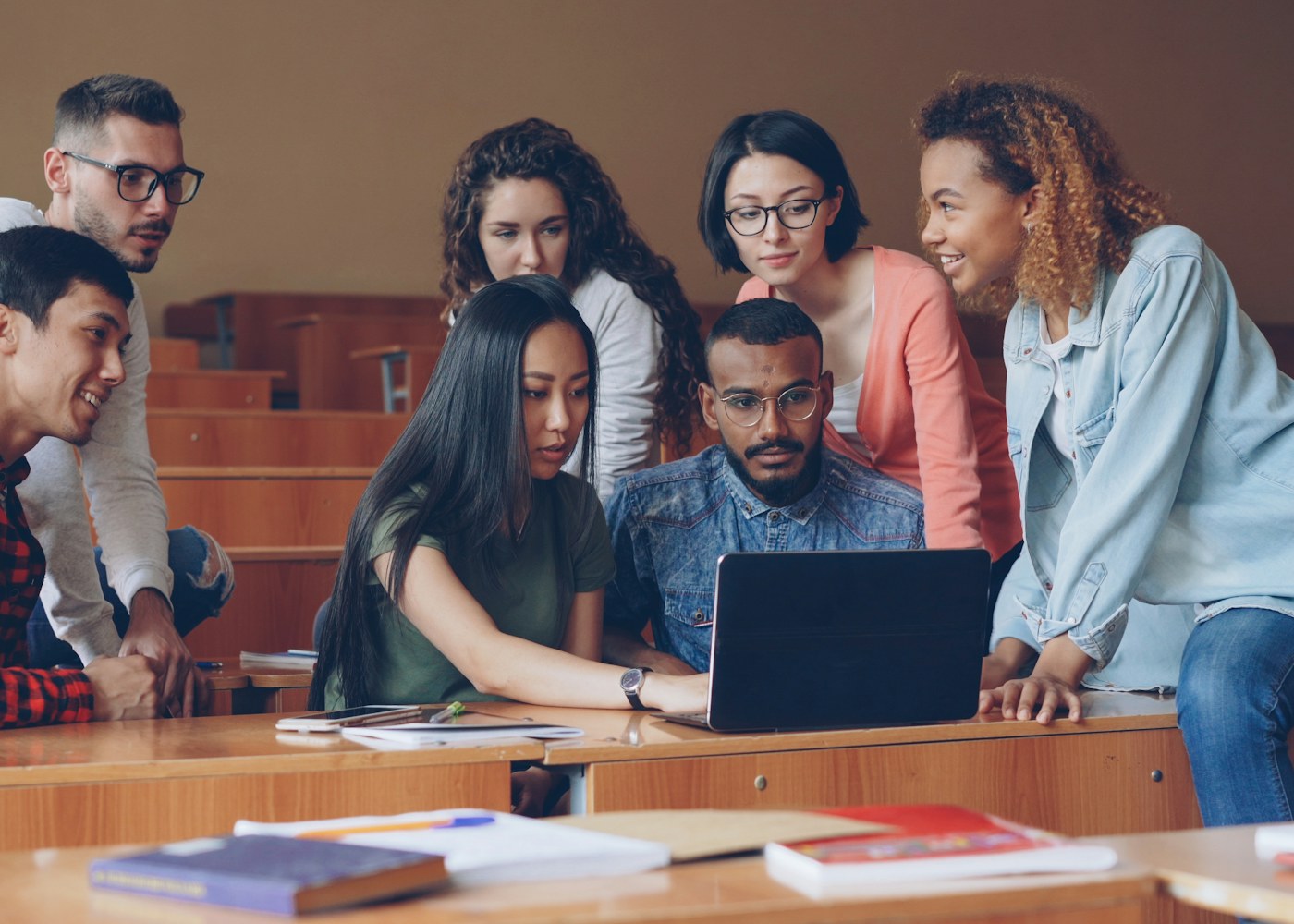 A diverse group of students collaborating around a laptop